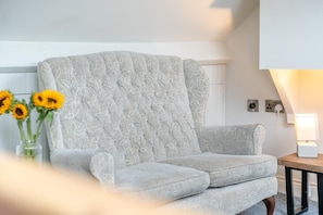A modern living room with a grey upholstered sofa, a vase with sunflowers, and a table lamp. - 1 Bed in Whitby (oc-s32880) (Whitby)