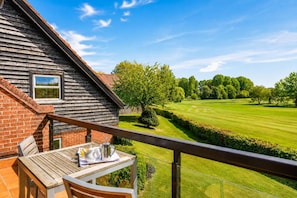 A wooden deck with a table and chairs, overlooking a well-manicured lawn and a golf course. - 2 Bed in Barnham Broom (oc-s42613) (Barnham Broom)