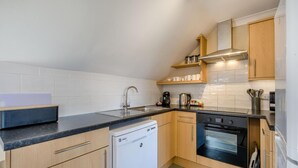 Cocina compacta con lavavajillas, estufa y cafetera.