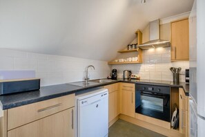 A compact kitchen with a dishwasher, stove, and coffee maker. - 3 Bed in Barnham Broom (oc-s42615) (Barnham Broom)
