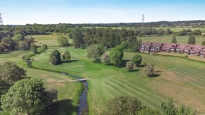 A rural landscape with a river, trees, and a row of red-roofed buildings. - 3 Bed in Barnham Broom (oc-s42615) (Barnham Broom)