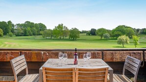 Un área de comedor al aire libre con mesa y sillas, con vistas a un campo de golf.