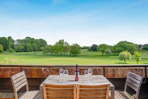 An outdoor dining area with a table and chairs, overlooking a golf course. - 3 Bed in Barnham Broom (oc-s42615) (Barnham Broom)