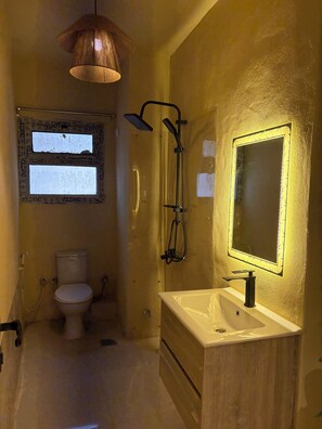 A bathroom with a toilet, a sink, a shower, and a mirror. - Canguu Bali Apartment Exora Spark  (Cairo Governorate)