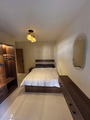 A bedroom with a bed, wardrobe, and a mirror on the wall. - Canguu Bali Apartment Exora Spark  (Cairo Governorate)