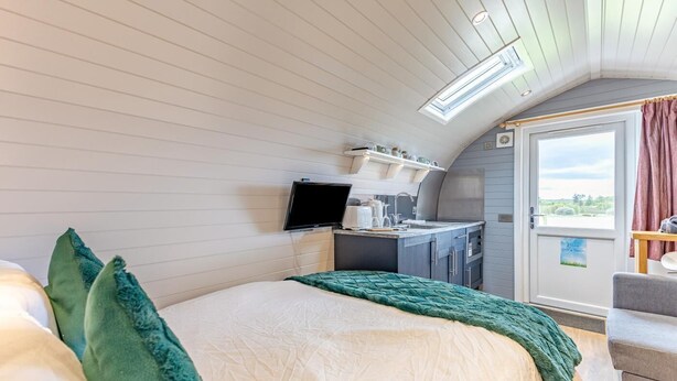A bedroom with a bed, a television, a kitchenette, and a balcony with curtains. - 1 Bed in Forfar (oc-t34622) (Forfar)