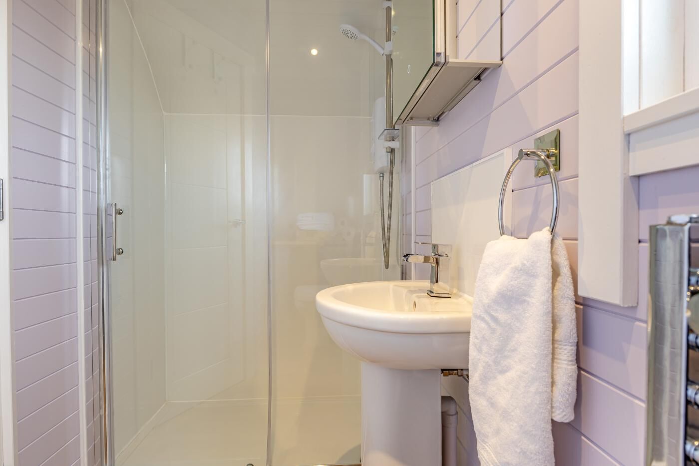 Une salle de bain moderne avec une douche à parois de verre, un lavabo blanc et un porte-serviettes.