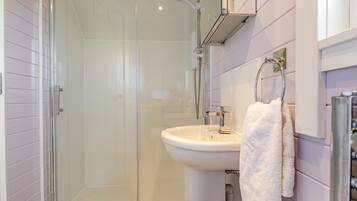 Une salle de bain moderne avec une douche à parois de verre, un lavabo blanc et un porte-serviettes.