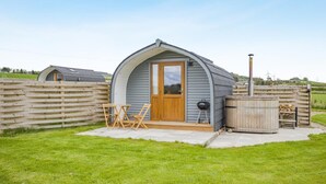 A small, single-story building with a sloped roof, a wooden door, and a patio area with a table and chairs. - 1 Bed in Forfar (oc-t34622) (Forfar)