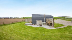 A modern building with a sloped roof, a small outdoor seating area, and a paved driveway. - 1 Bed in Forfar (oc-t34622) (Forfar)