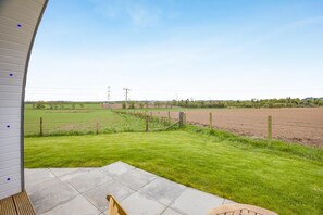 A patio area with a view of a farm field and power lines in the distance.
