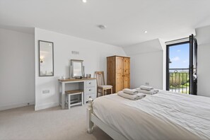 A bedroom with a bed, a desk, a chair, a wardrobe, and a balcony with a view. - 1 Bed in Milton Abbas (oc-v35014) (Milton Abbas)
