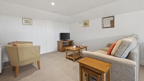 A living room with a sofa, armchair, coffee table, and TV stand. - 1 Bed in Milton Abbas (oc-v35014) (Milton Abbas)