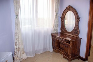 Habitació amb un armari de fusta, un mirall i cortines de tela fina.