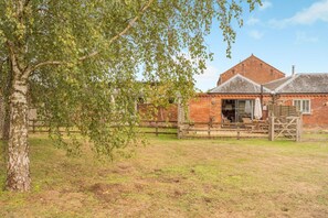 Ein Backsteinhaus mit einer breiten, offenen Veranda und einem Holzzaun.