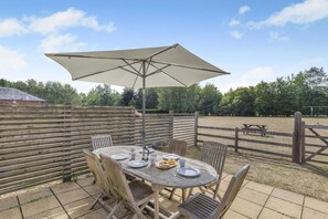 An outdoor patio with a round table, chairs, and a large umbrella. - 3 Bed in Cranmer (oc-s45787) (Cranmer)