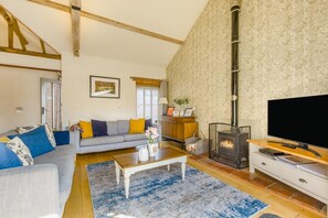 A living room with a sofa, coffee table, fireplace, television, and a patterned wall. - 3 Bed in Cranmer (oc-s45787) (Cranmer)
