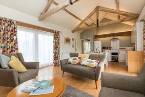 A living room with a sofa, armchairs, a coffee table, and a kitchen in the background. - 2 Bed in Cranmer (oc-t45788) (Cranmer)