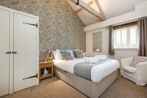 A bedroom with a large bed, a wardrobe, a nightstand, a window with curtains, and a mirror on the wall. - 2 Bed in Cranmer (oc-t45788) (Cranmer)