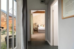 A hallway leading to a bedroom with a bed, a nightstand, and a lamp. There is a window on the left side. - 2 Bed in Cranmer (oc-o45790) (Cranmer)