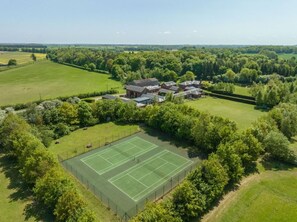 An aerial view of a residential area with a tennis court and multiple houses surrounded by greenery. - 2 Bed in Cranmer (oc-o45790) (Cranmer)