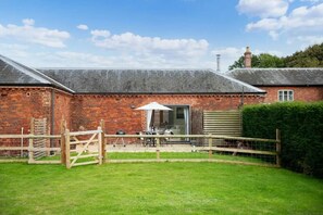 A brick building with a covered patio area, a wooden gate, and a hedge. - 2 Bed in Cranmer (oc-o45790) (Cranmer)