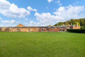 Un vaste champ dégagé, avec un bâtiment en briques en arrière-plan.