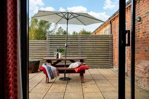 An outdoor patio area with a wooden table, a bench, a picnic table, and a large umbrella. - 2 Bed in Cranmer (oc-w45791) (Cranmer)