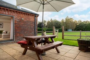 A wooden picnic table with a canopy, a brick wall, and a view of a green lawn. - 2 Bed in Cranmer (oc-w45791) (Cranmer)