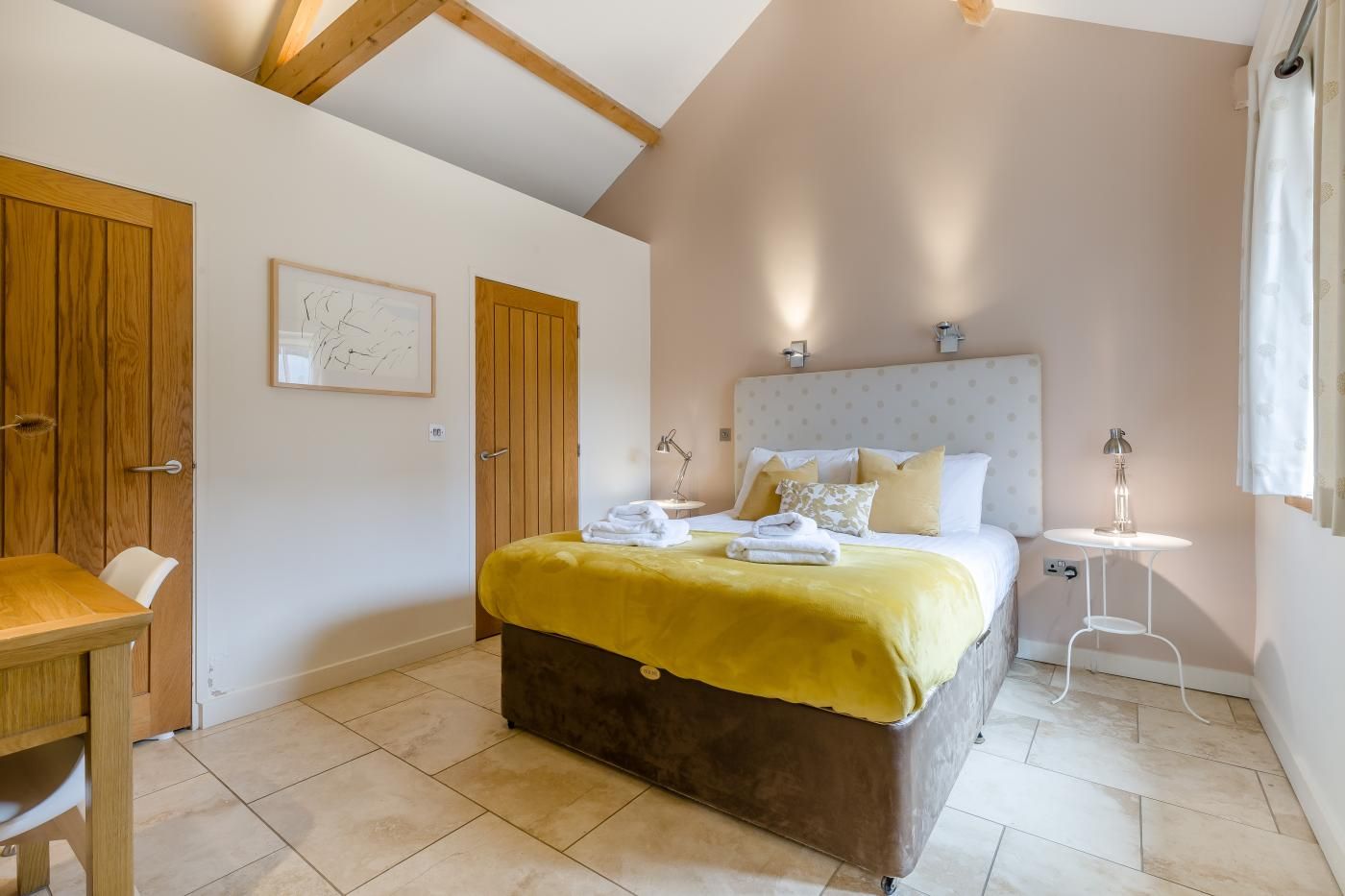 A bedroom with a bed, bedside table, and a desk.