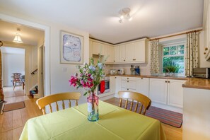A kitchen with white cabinets, a dining table with a yellow tablecloth, and a vase with flowers. - 2 Bed in Newtyle (oc-b45543) (Newtyle)