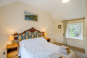 A bedroom with a large bed, two bedside tables with lamps, a framed landscape painting, a door, and a window with curtains. - 2 Bed in Newtyle (oc-b45543) (Newtyle)