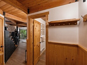 A wooden interior with a hallway leading to a room with a fireplace, a coat rack, and a view of a balcony. - Escape to Ptarmigan Village 36 (Whitefish)