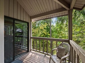 A covered porch with a wooden deck, a glass door leading to a deck area, and a chair. - Escape to Ptarmigan Village 36 (Whitefish)