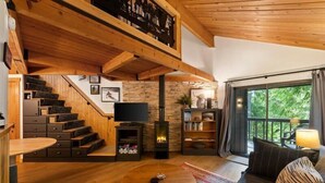 Ein Holzinnenraum mit Kamin, einer Couch, einem Fernseher und einer Treppe.