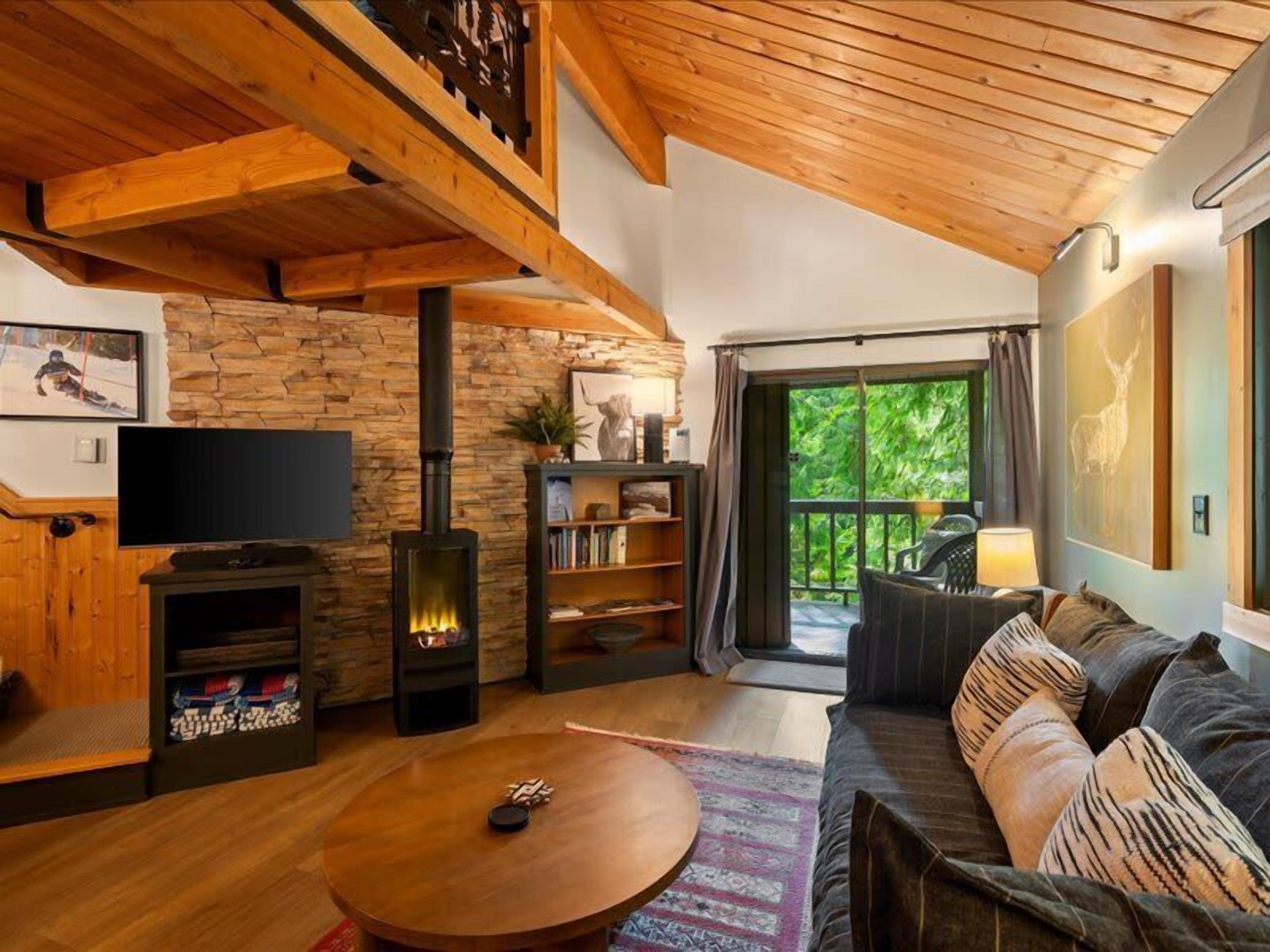 A cozy living room with a fireplace, a sofa, a television, and a bookshelf.