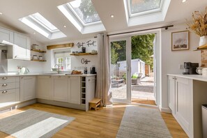 Eine moderne Küche mit Oberlichtern, einer Kaffeestation und Blick zum Garten.
