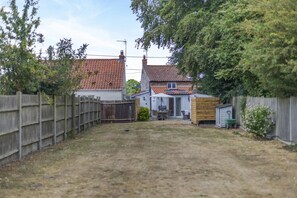 A backyard with a wooden fence, a shed, and a house with a tiled roof. - 2 Bed in Great Massingham (oc-a45882) (Great Massingham)
