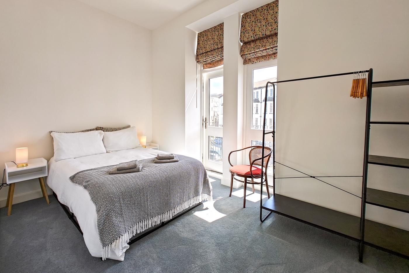A bedroom with a bed, bedside tables, a chair, and a window with a view.
