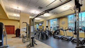Uma academia com esteiras, elípticos e equipamentos de musculação.