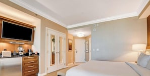 Ein Hotelzimmer mit Bett, Fernseher, Schreibtisch mit Kaffeemaschine und einem durch eine Tür einsehbarer Badezimmer.