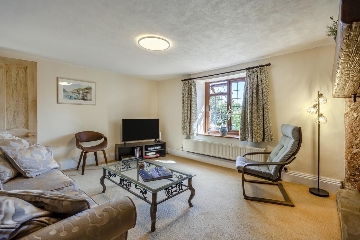 A living room with a sofa, two chairs, a coffee table, a television, and a floor lamp.