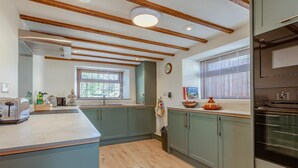A modern kitchen with wooden beams, a large island, and built-in appliances. - 2 Bed in Cheddar (oc-v45773) (Cheddar)