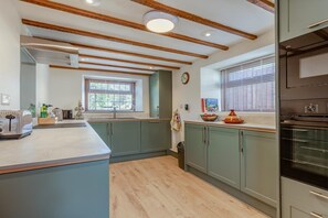 A modern kitchen with wooden beams, a large island, and built-in appliances. - 2 Bed in Cheddar (oc-v45773) (Cheddar)