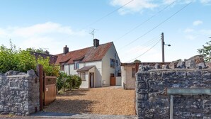 A residential property with a stone wall entrance, a gravel driveway, and a house with a tiled roof. - 2 Bed in Cheddar (oc-v45773) (Cheddar)
