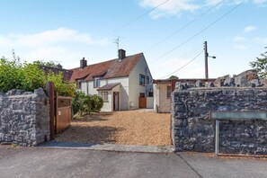 A residential property with a stone wall entrance, a gravel driveway, and a house with a tiled roof. - 2 Bed in Cheddar (oc-v45773) (Cheddar)