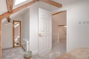 A room with a white door, a radiator, a hanging light fixture, and a ceiling with exposed wooden beams. - 3 Bed in Allendale (oc-b45877) (Allendale Town)