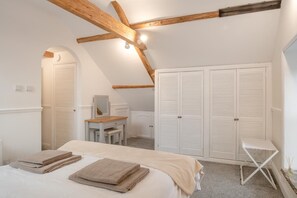 Ein Schlafzimmer mit einem Bett, einem Schreibtisch, einem Stuhl und einem Kleiderschrank.