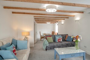 A living room with a sofa, a coffee table, and a dining area in the background. - 3 Bed in Allendale (oc-b45877) (Allendale Town)