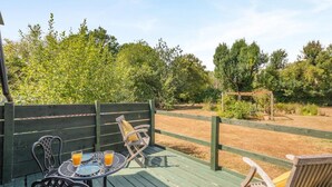 An outdoor seating area with a table and chairs, surrounded by a wooden deck and a fenced garden. - 1 Bed in Laddingford (oc-s45858) (Laddingford)